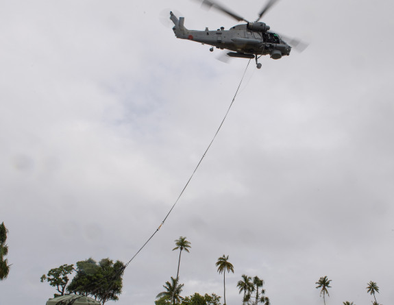 A Seasprite helicopter lifts a water tank from a field in Tokelau
