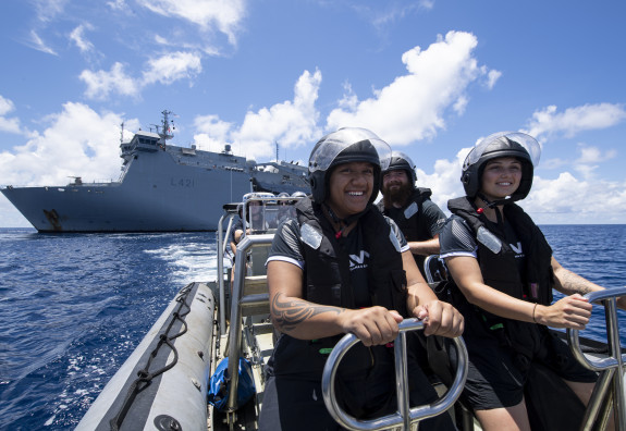 Sailors on a Rigid Hull Inflatable Boat on a nice day with HMNZS Canterbury behind them