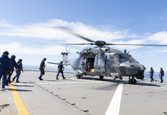 NH90 helicopter on a flight deck of a ship with personnel around
