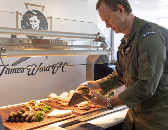 The Base Commander selects a pulled pork burger from a stand at the James Ward VC Food Court at Base Ohakea