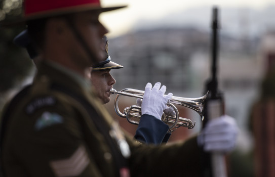 A New Zealand Army soldier performs the bugle behind another soldier during an Anzac Day commemoration in 2021