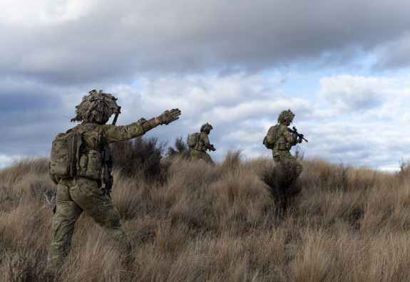 A New Zealand Army soldier performs a hand signal to his team while out in the tussock of the Waiouru Military Training Area 