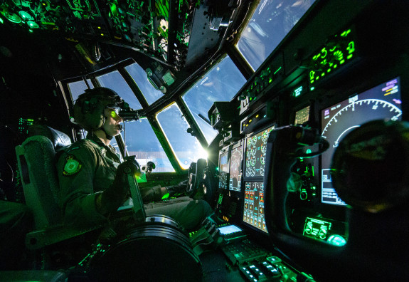 A Royal New Zealand Air Force pilot on the flight deck of a C-130H(NZ) Hercules aircraft wears night vision goggles during flight