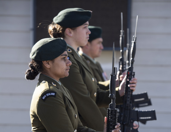 New Zealand Army soldiers on parade in service dress present arms with rifles and bayonet. 