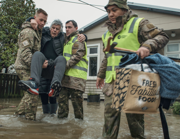 Soldiers from 3rd Combat Service Support Battlion (3CSSB) assist a Buller District resident evacuate from their home following flooding.