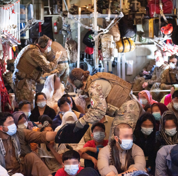 NZDF personnel check details with the evacuees on board a Hercules aircraft.