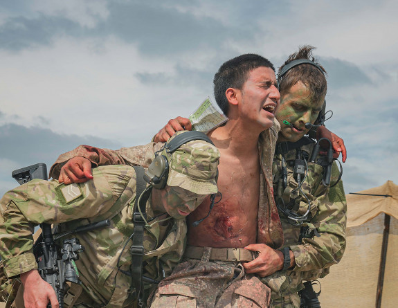 Two soldiers support their injured comrade during Exercise Foxhound