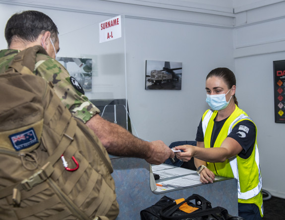 A New Zealand Army soldier in uniform hands over identification to the Royal New Zealand Air Force personnel before boarding their flight.