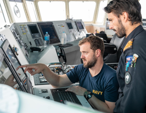 Two sailors point to screen on the bridge of HMNZS Wellington of as