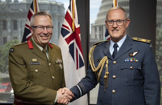 Colonel Paul Dragicevich and the Chief of Defence Force Air Marshal Kevin Short shake hands - in the background three flags