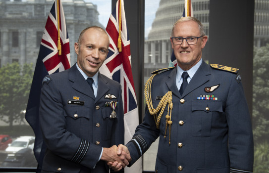 Wing Commander Brett Clayton and the Chief of Defence Force Air Marshal Kevin Short shake hands - in the background three flags