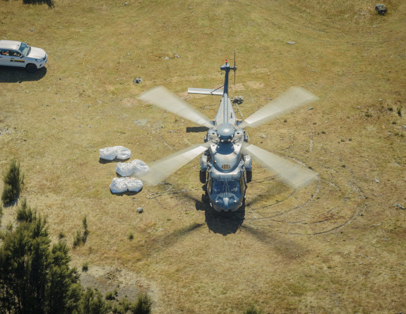An NH90 helicopter on the ground before picking up loads move. To the left of the image is a ute. 
