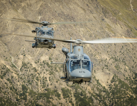 An NH90 and A109 helicopter fly in the mountain range