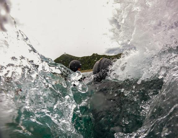 Two HMNZS Matataua coxswain in white water of the relentless waves of Piha Beach in Auckland.