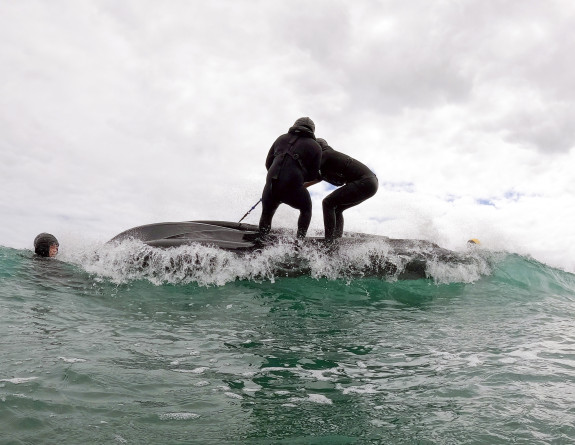 Two of HMNZS Matataua coxswains train to flip the zodiac the right way up in the waves at Auckland's Piha Beach.