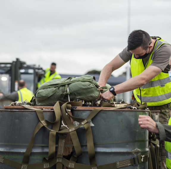 Two personnel secure a parachute to the top of the cargo which is to be dropped from the Hercules.