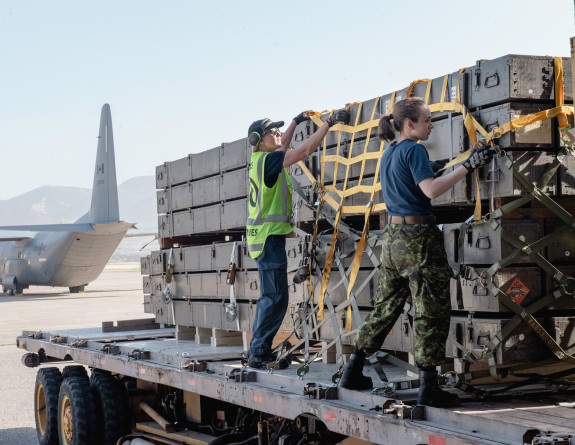 Two personnel prepare loads of supplies. 