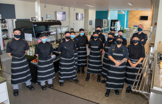 Navy Chefs of the Vince McGlone Galley stand in front of the food collection counters at Devonport Naval Base.