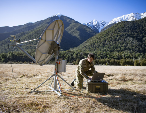An aviator sets up communications with a satellite dish and a computer in Dip Flat.