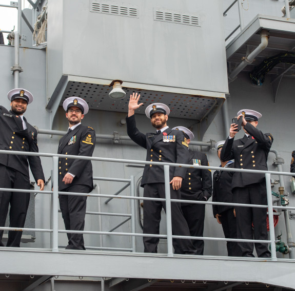 Some of the Ship's Company of HMNZS Te Mana wave to family as they arrive at Devonport Naval Base