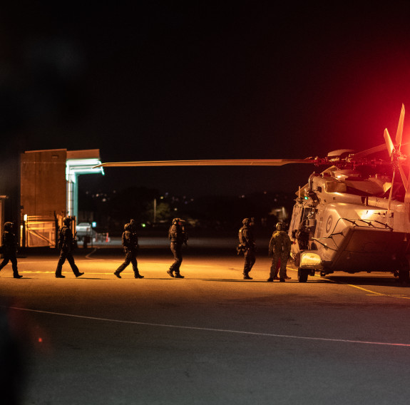 Members of the AOS and STG cross the tarmac to board an NH90 helicopter