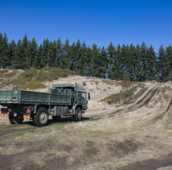 The MHOV prepares to go up a hill with trees in the background.