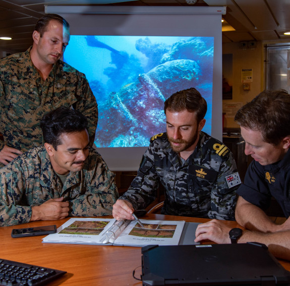 Staff Sergeant Keith Bobowick (USMC), Sergeant Ricardo De La Torre (USMC), Liuetenant Matthew Smith (RAN),  Petty Officer Jamie Howden (RNZN) identifying the types of ERW found in Nanumea Lagoon.