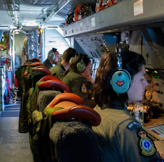 Air Force crew wearing dark green uniform look at information on monitors on board the P-3K2 Orion aircraft.