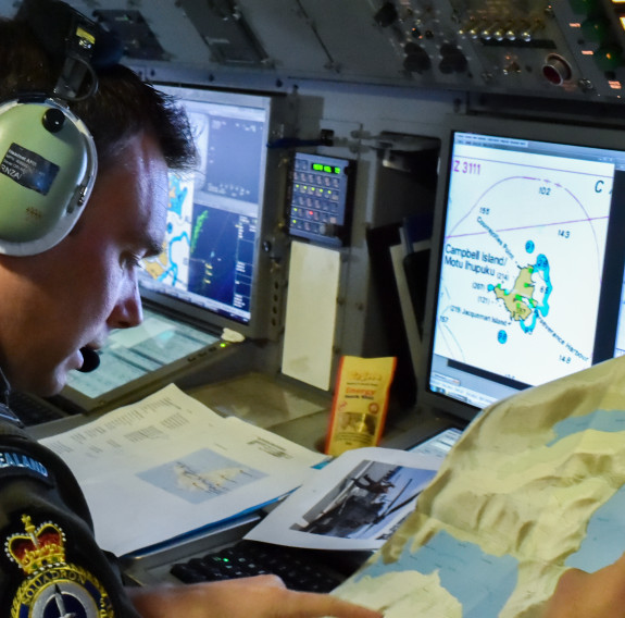 An aviator inspects a map and monitors on board the P-3K2 Orion aircraft during a flight.