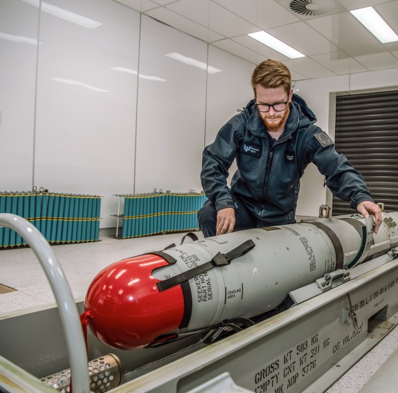 Air personnel unstrapping a missile 