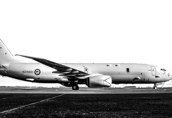 A Royal New Zealand Air Force P-8A Poseidon aircraft. Image in black and white and taken from standing on the right side of the aircraft. 