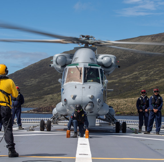 Five personnel and the Seasprite helicopter preparing for take off on the flight deck of HMNZS Canterbury.