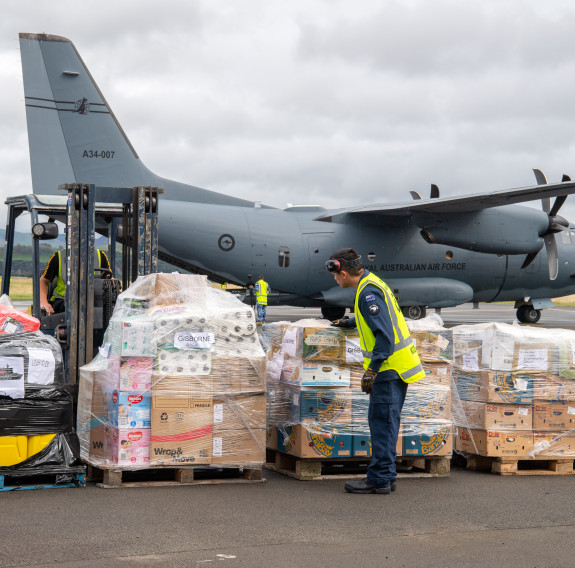 Four pallets and a forklift sit on the tarmac in front of the RAAF C-28 Spartan, a large grey aircraft with a propeller on each wing.