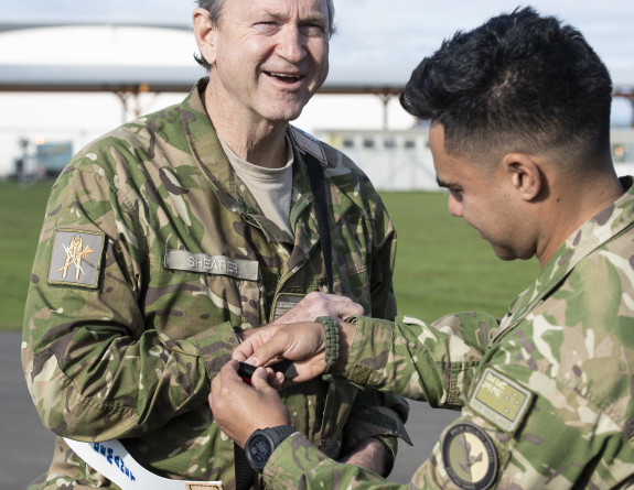 Group Captain Rob Shearer starts getting ready for the bite by putting on protective equipment. Another handler assists with this as Rob smiles at the camera.