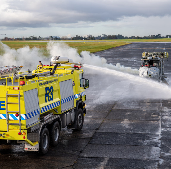 Base Auckland's Rescue Three firetruck sprays water on the aircraft as a smoke is coming from the rear of the aircraft to simulate fire.