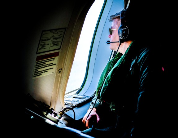 A Royal New Zealand Air Force aviator looks out the window of a P-8A Poseidon aircraft. 
