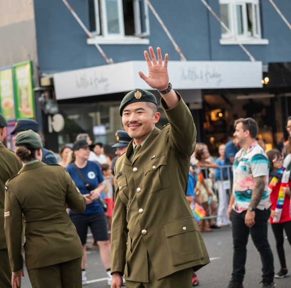A soldier proudly waves to the crowd as the parade turns at a crossroads in Auckland.
