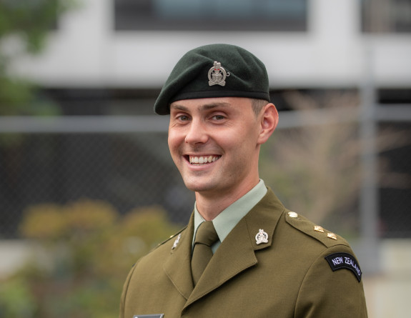 A man wearing NZ Army uniform smiles at the camera.