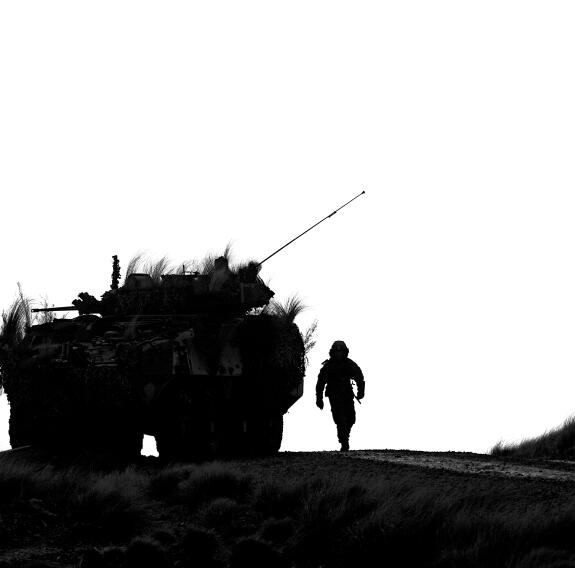 Soldier walking next to LAV in silhouette.
