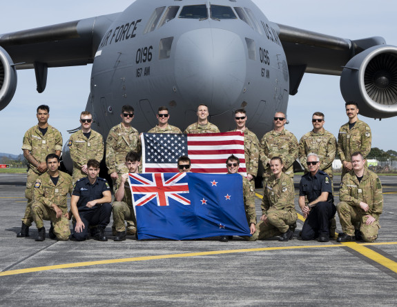 The USAF and RNZAF team hold their corresponding countries flag in front of a USAF aircraft.