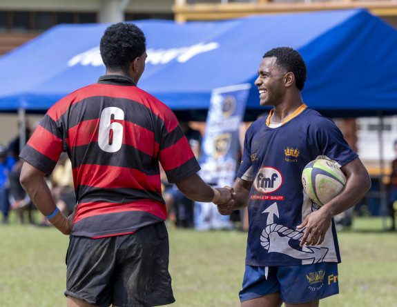 Rugby players shake hands and share smiles.