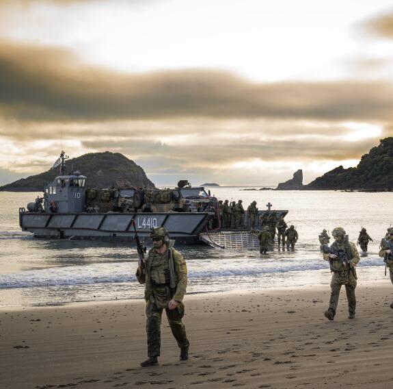 Soldiers walking along beach after amphibious landing