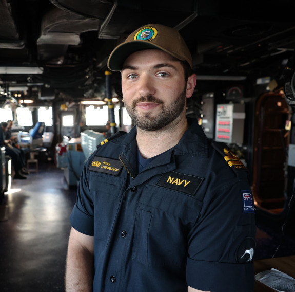 LT Cunningham on the bridge of a ship wearing RNZN uniform and a Pacific Partnership cap.