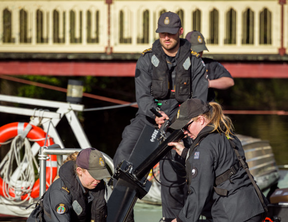 Three sailors prepare equipment on the Zodiac dinghy.