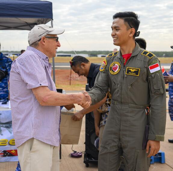 Two men shake hands and share smiles on the air field during Exercise Pitch Black open day