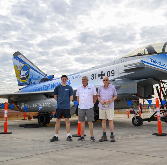 Three people stand in front of a German Eurofighter at the Pitch Black open day.