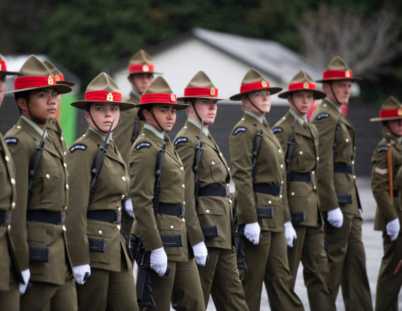 New Zealand Army soldiers stand in a line formation with weapons. 