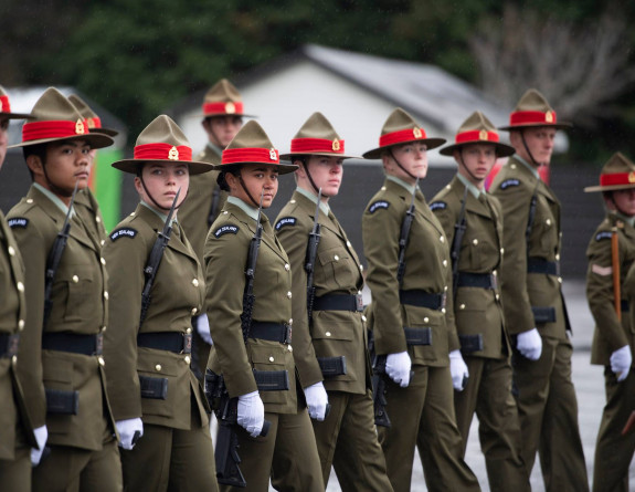 New Zealand Army soldiers stand in a line formation with weapons.