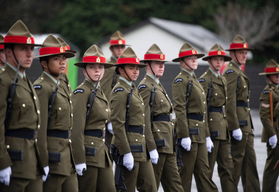 New Zealand Army soldiers stand in a line formation with weapons. 