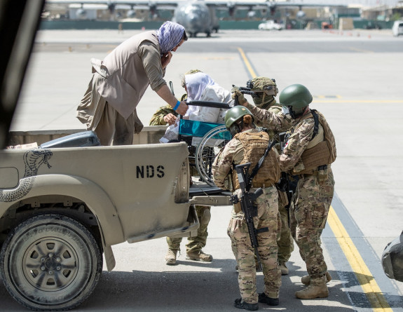  Four New Zealand Defence Force personnel help get an evacuee in a wheelchair get off a truck